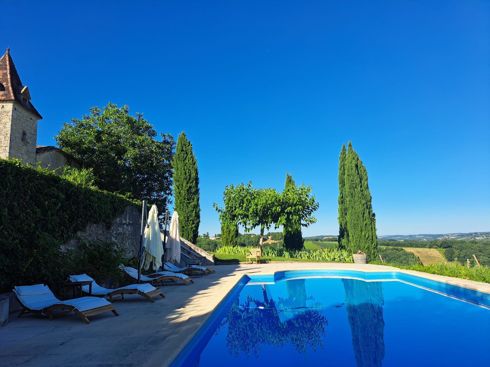 The infinity-style pool at Mongaudon with loungers and the pigeonnier tower behind